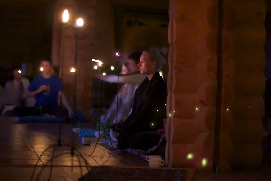Skupinová meditácia v šere ášramu, pri svetle sviečok