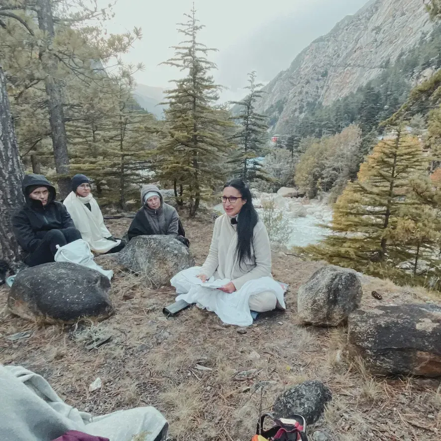 A small group sitting on rocks in a mountain valley among conifers