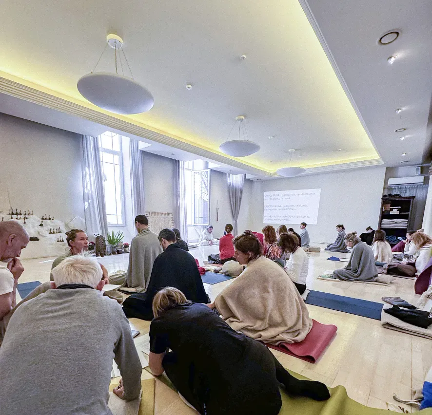 Course participants sitting on mats and listening to a talk